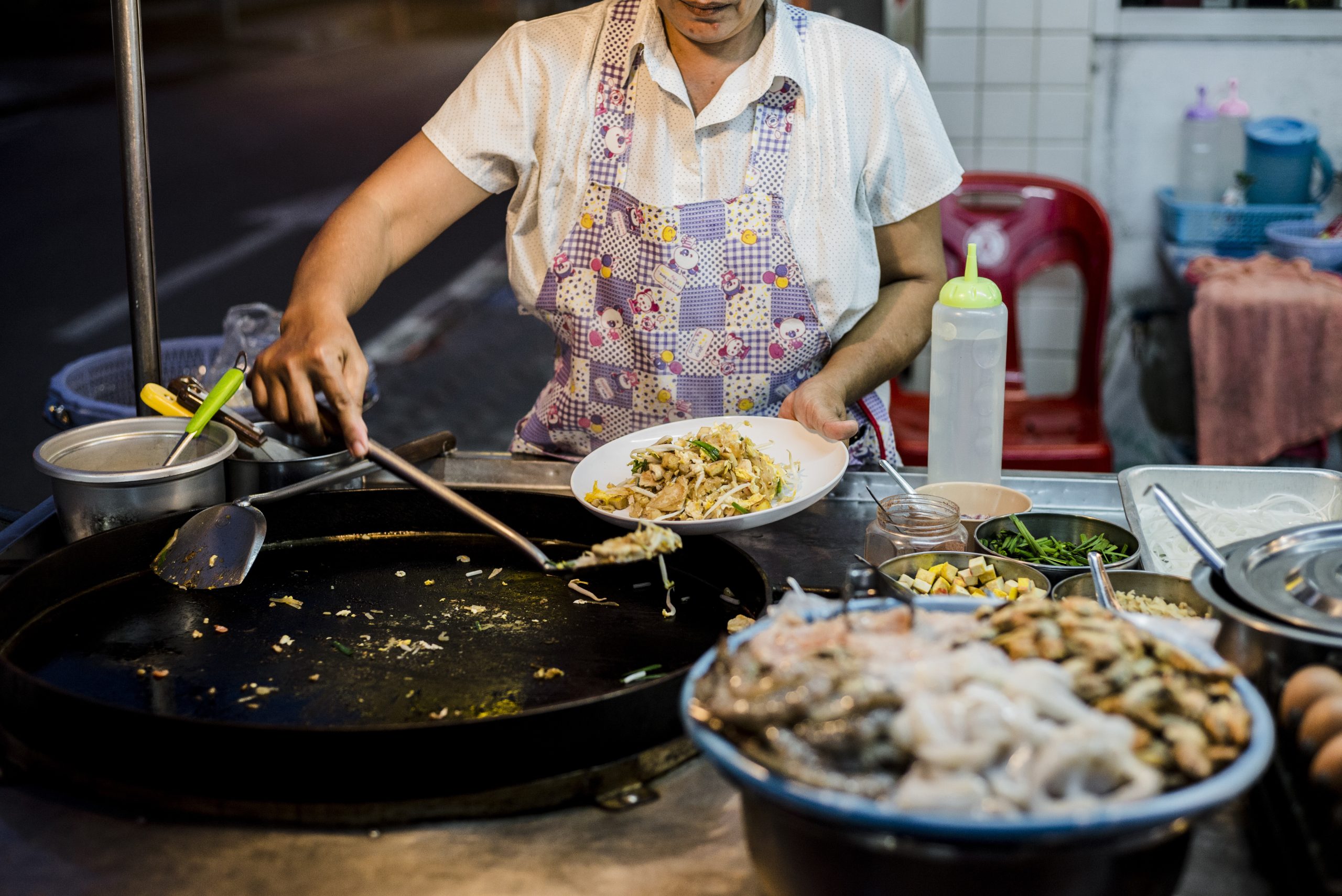 Street vendor skillfully whipping up a delicious meal in a bustling night market